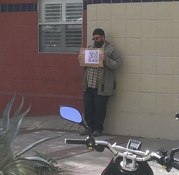 And here's a homeless hipster at SXSW 2013 holding a sign with a QR code...